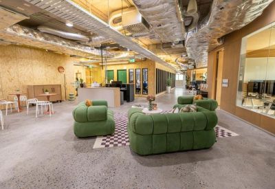 Coworking lounge with green upholstered seating and timber wall paneling.