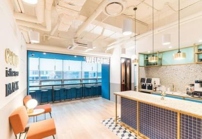 Modern reception area with a tiled counter, coffee machines, and blue accents.