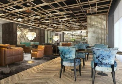 Chic lounge area with blue velvet chairs, leather armchairs, and a decorative wood-lattice ceiling.