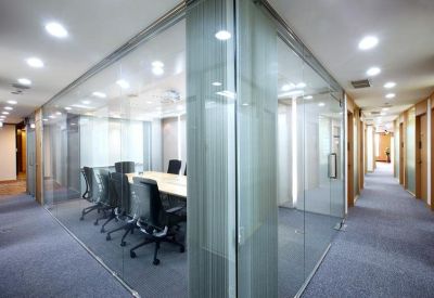 Glass-walled conference room with a long table and black ergonomic chairs.