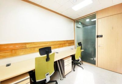 Bright office space with a long shared desk and frosted glass partition.