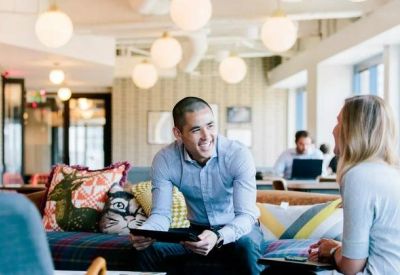 Vibrant communal lounge with colorful cushions, orb lighting, and coworkers chatting.