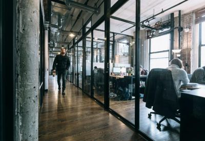 Industrial style corridor with glass-walled offices and polished wood floors.