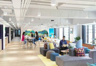 Bright coworking area with colorful sofas, a high-top table, and mural art.