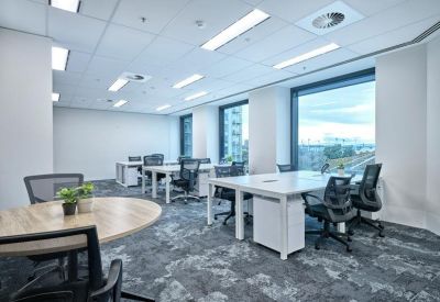 Spacious open-plan workspace with multiple desks and floor-to-ceiling windows.