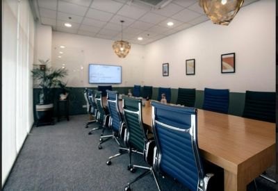 Professional meeting room featuring a long wooden table and blue leather chairs.