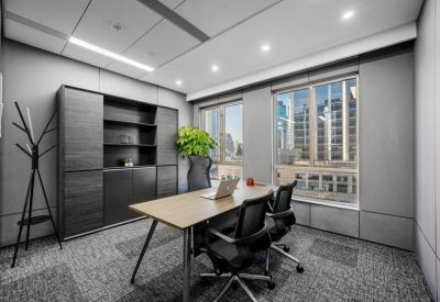 Private office suite featuring a wooden desk, black chairs, and large windows overlooking the city.