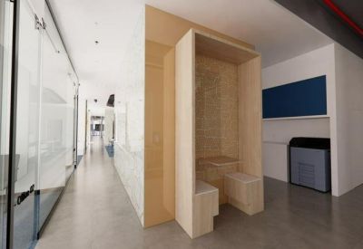 Bright corridor showing a light wood privacy booth and glass office partitions.