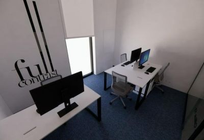 Modern coworking area with white desks, green living walls, and an industrial ceiling.