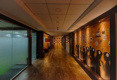 Modern office corridor featuring warm wooden flooring and a mural of silhouetted figures.
