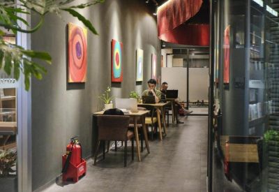 Contemporary cafe-style breakout space with large windows and a blue cloud ceiling sculpture.