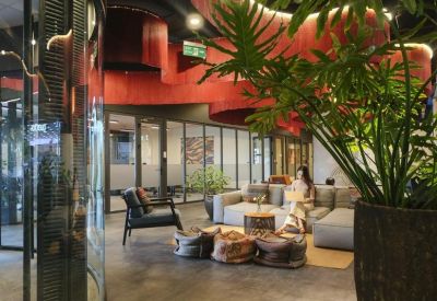 Quiet corridor workspace with wooden desks, colorful abstract paintings, and a view into glass-walled offices.