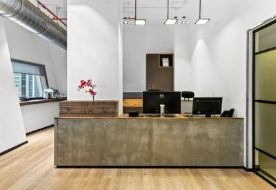 Professional reception desk with a concrete finish, computer monitors, and decorative orchid.
