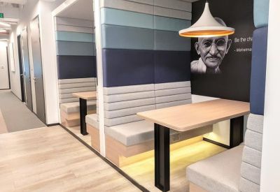 Private coworking booths with padded walls, light wood tables, and a mural of Mahatma Gandhi.