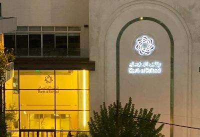 Bank of Jordan building entrance with glowing signage and yellow interior lighting.