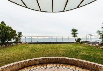 Backyard lawn with a view of the sea and islands through a glass fence.