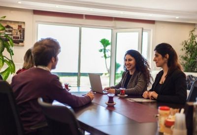 Team members having a discussion at a wooden table with a view of the garden.