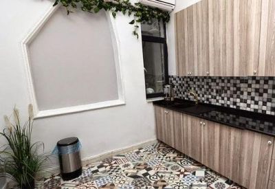 Modern communal kitchen with patterned tile flooring and light wood cabinetry.