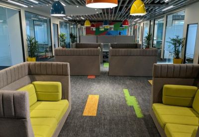 Communal breakout area with high-backed grey sofas and bright lime green cushions.