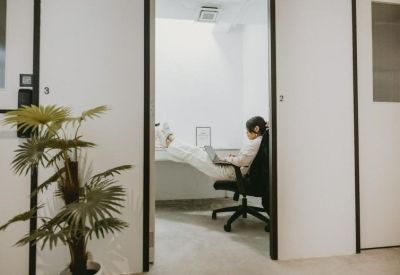 Private office pod showing a person working at a desk with an ergonomic chair.