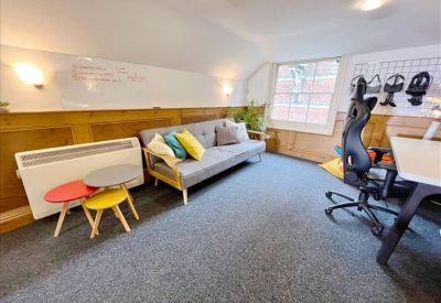 Creative lounge area featuring a grey sofa, colorful nesting tables, and a whiteboard wall.
