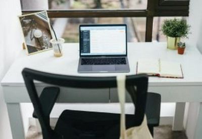 Single desk setup by a large window with a laptop and notebook.