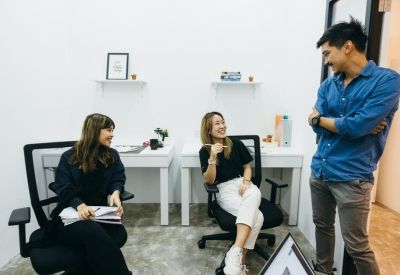 Private office suite with three people collaborating near white desks.