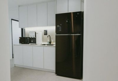 Communal kitchen area featuring white cabinetry and a large black refrigerator.