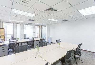 Bright open-plan office featuring rows of white desks and ergonomic black mesh chairs.