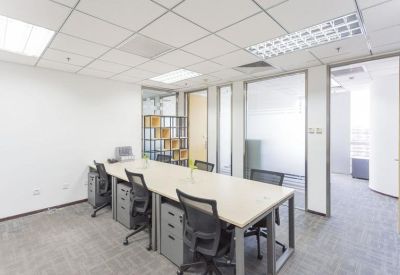 A shared workspace area with multiple desk clusters and grey carpet flooring.