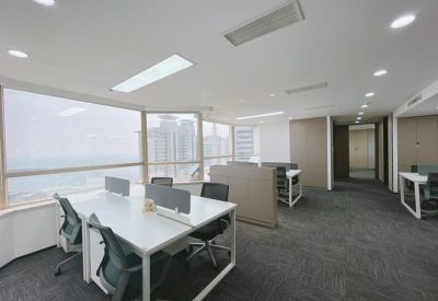 Open-plan office with large windows providing views of the city skyline.