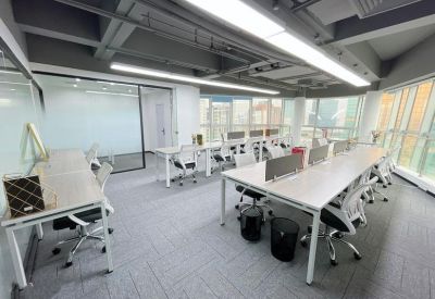 Bright open-plan workspace with multiple white desks and ergonomic chairs.