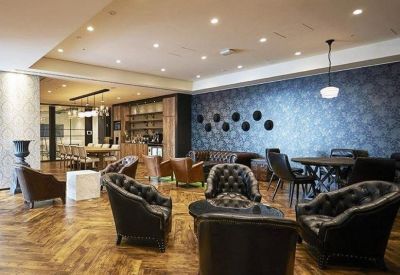 Spacious lounge area with tufted leather armchairs and polished herringbone wood floors.