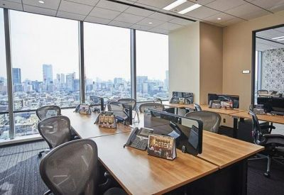 Bright open-plan office with wooden desks and large windows overlooking the city.