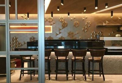 Modern cafe bar with high stools and a decorative geometric wall pattern.