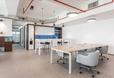 Communal break area with a kitchen island, bar stools, and long coworking table.