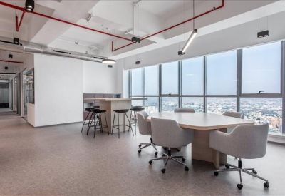 Large meeting room with a light wood table, grey armchairs, and industrial-style ceiling.