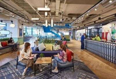 Bright reception area with a blue textured desk, colorful wall art, and comfortable lounge seating.