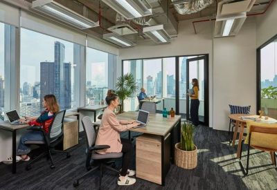 Bright private office with corner windows showing a cityscape and ergonomic workstations.