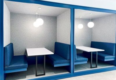 Semi-private blue upholstered meeting booths with white tables.