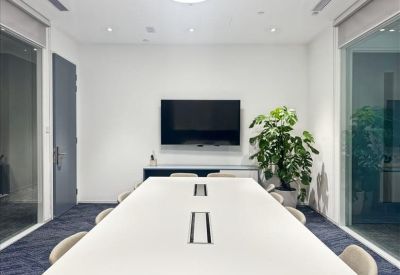 Bright conference room featuring a long white table and wall-mounted TV.