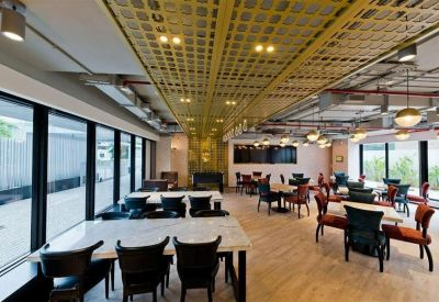 Spacious communal dining area with marble tables and decorative gold ceiling panels.