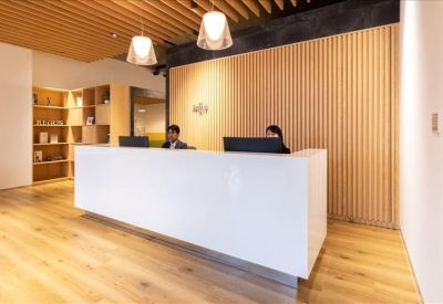 Modern white reception desk featuring warm wood-slat walls and pendant lighting.