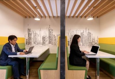 Semi-private work booths with green seating and illustrated city skyline murals.