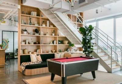 Breakout space with a pool table and floor-to-ceiling bookshelves under a staircase.