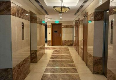 Marble-clad elevator lobby at Khalidiya Towers with decorative hanging bowl lamps.