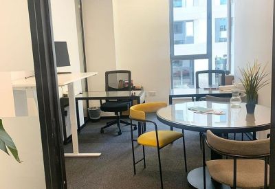 Bright workspace featuring a round meeting table, yellow chairs, and large windows.