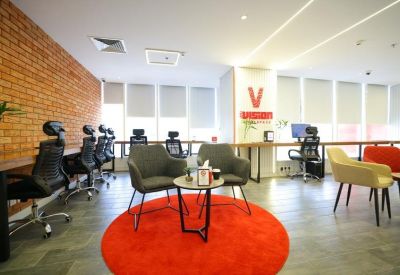 Contemporary lounge with grey armchairs and a vibrant red circular rug.