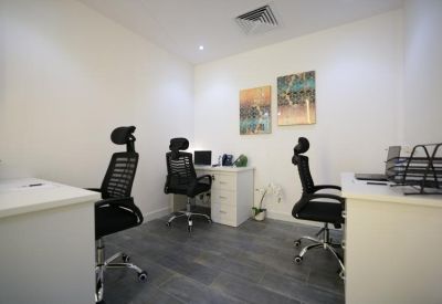Private office with three black ergonomic chairs and white desks.
