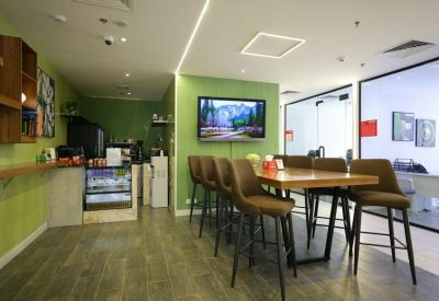 Vibrant green breakout area with high-top wooden tables and bar stool seating.